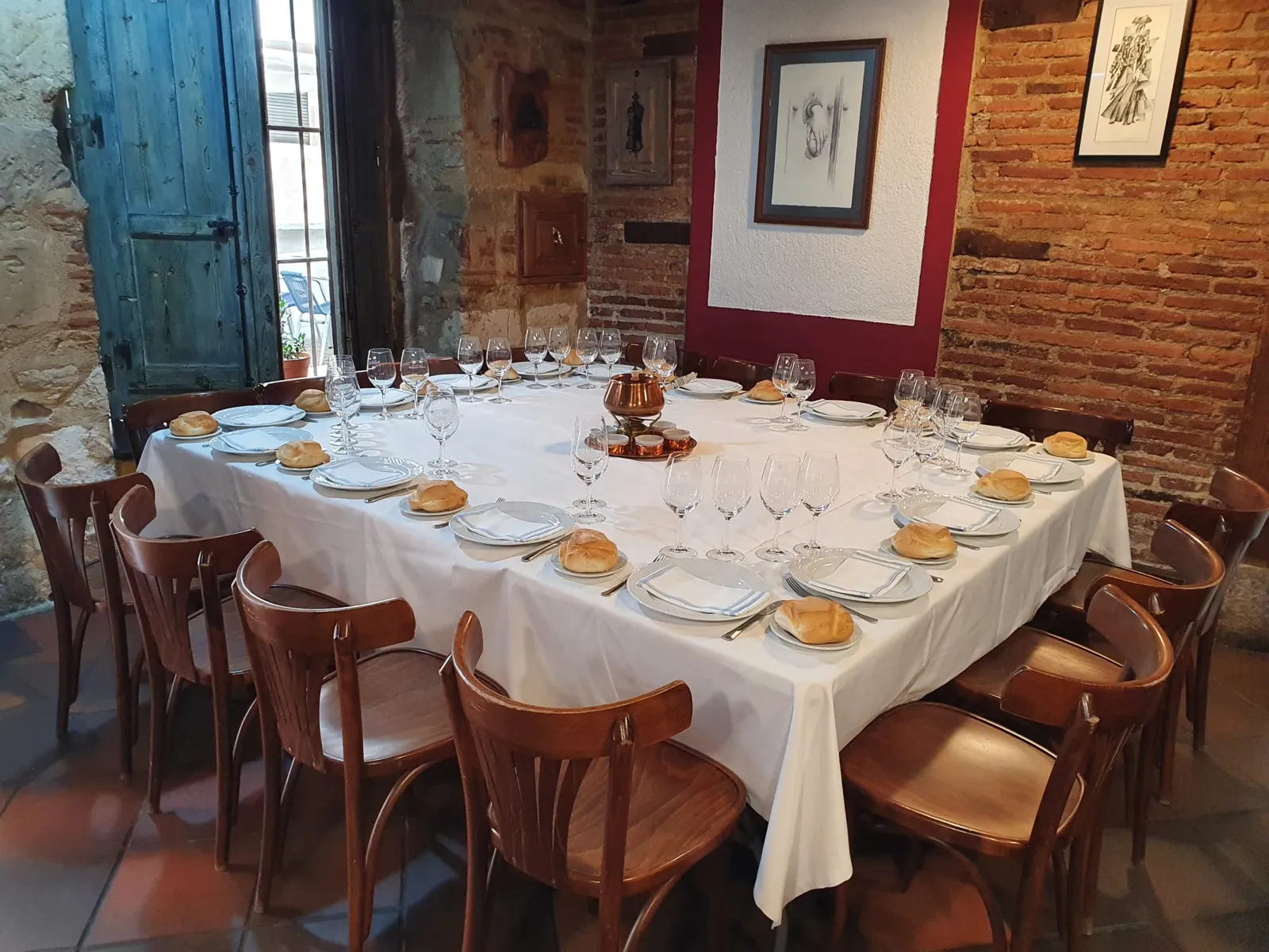 Mesa preparada para un grupo de doce junto a la ventana y la pared de ladrillo